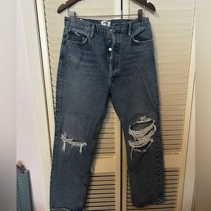 blue jeans with holes at the knees, fastened with buttons.